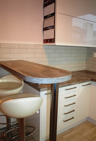 Białe meble połączone z wyspą w kolorze drewna